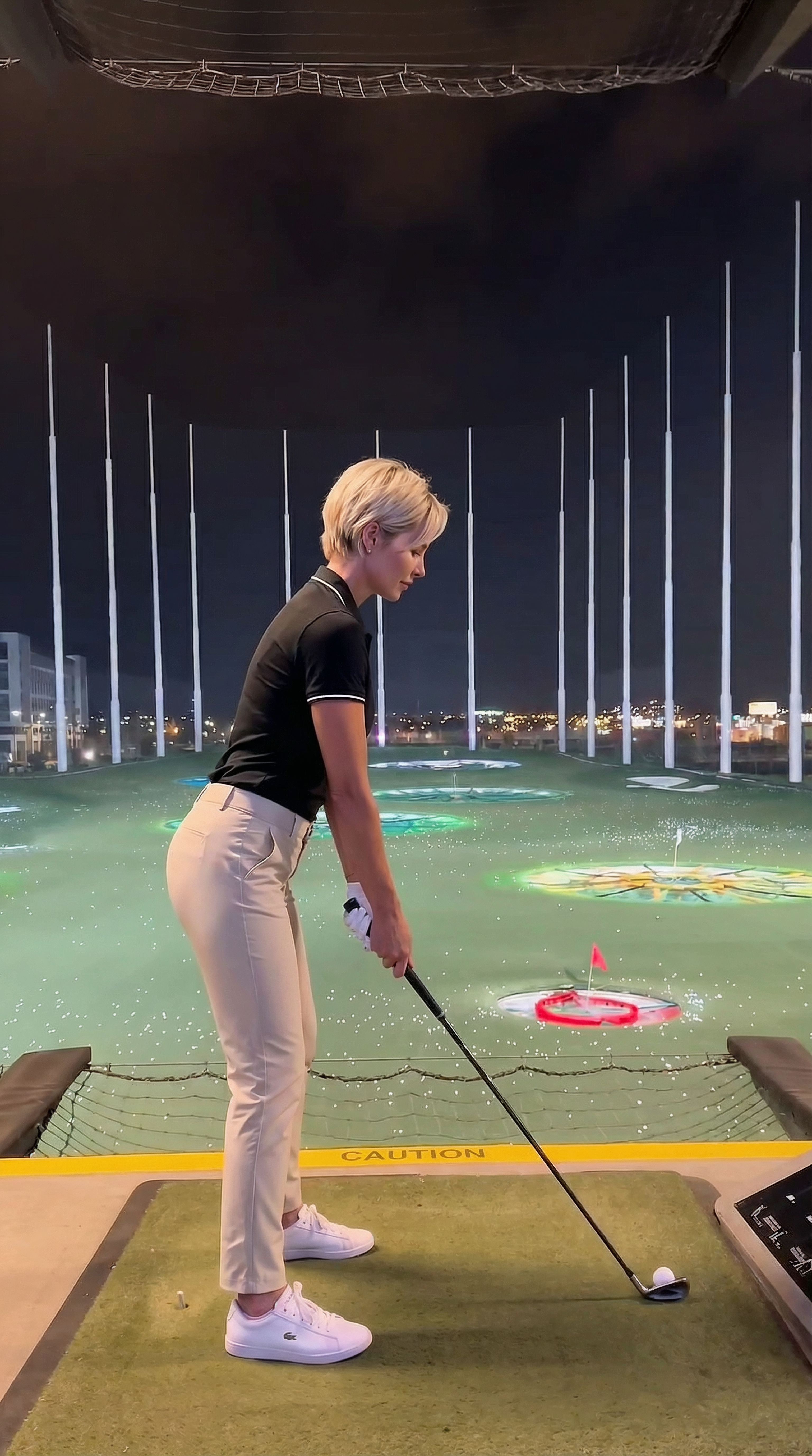 Deeanna Goff swinging at a night golf venue